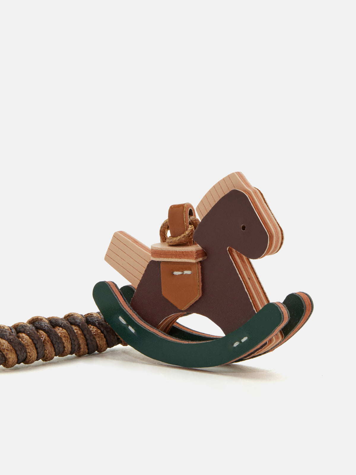 A wooden rocking horse keychain with a dark brown body, light natural wood accents, a dark green curved base, and a brown coiled cord, photographed on a clean white background.
